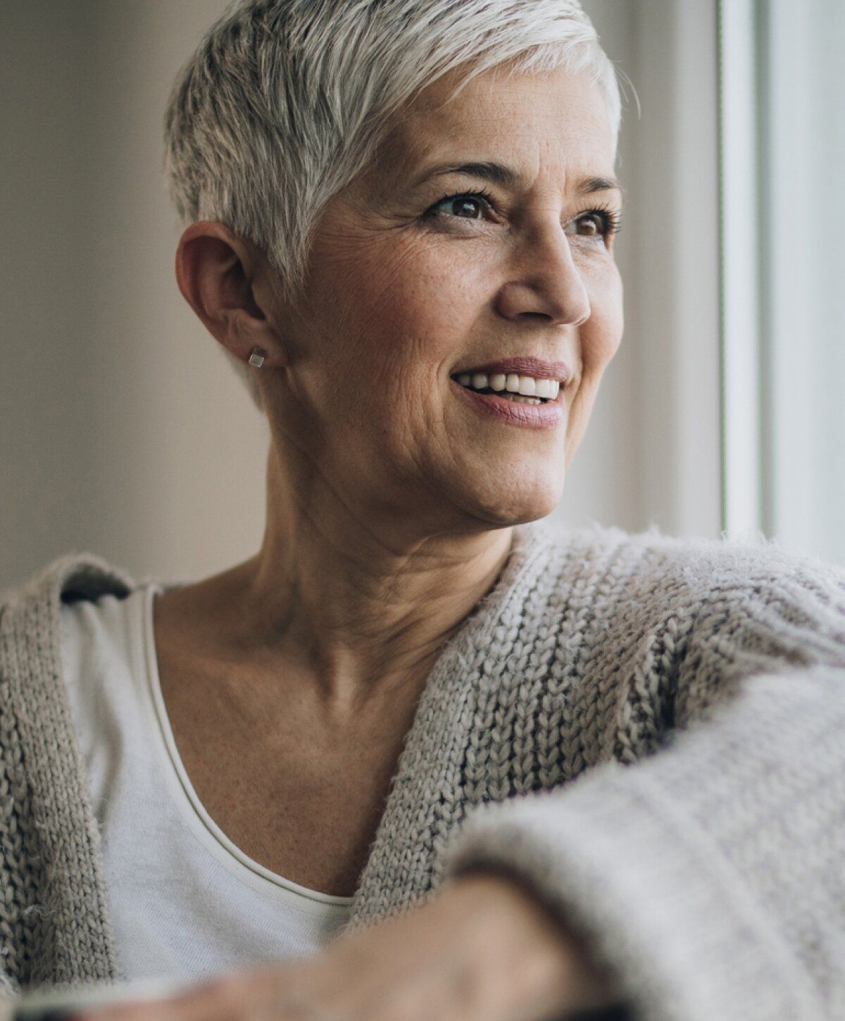 Smiling older woman near a window.