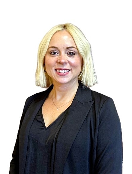 Smiling woman in a black blazer, professional setting.